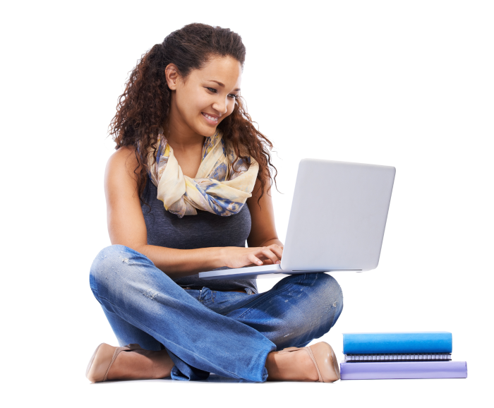 A student sitting on the floor cross-legged smiling and looking at a laptop