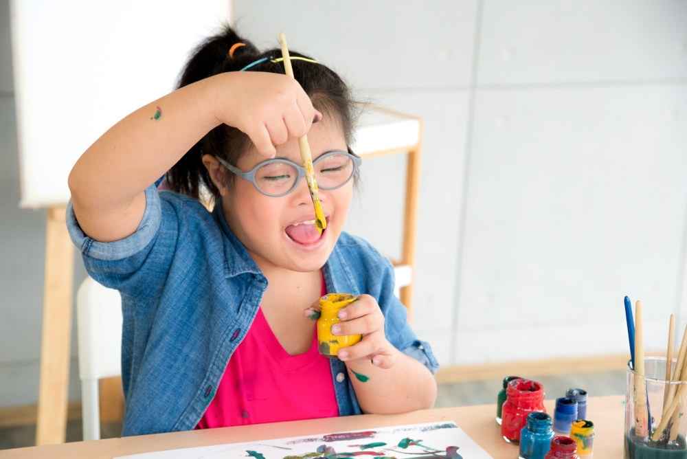 A student painting and looking intently at a paintbrush with paint