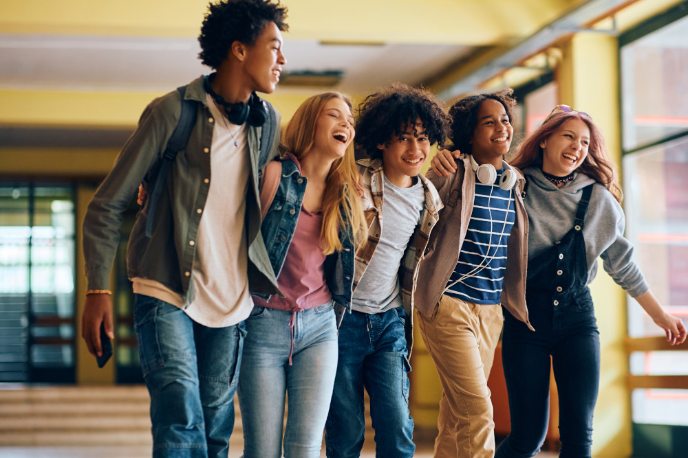Five students walking with their arms around each other.