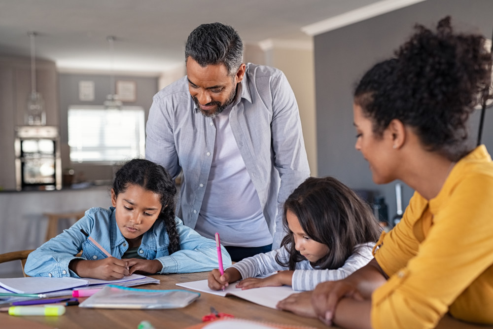 Two parents helping their two children complete their homework